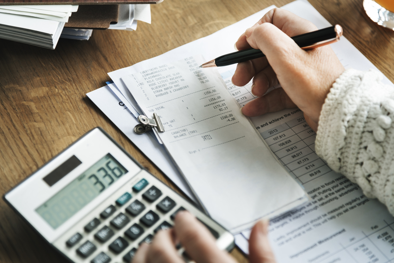 Person adding up bills with calculator