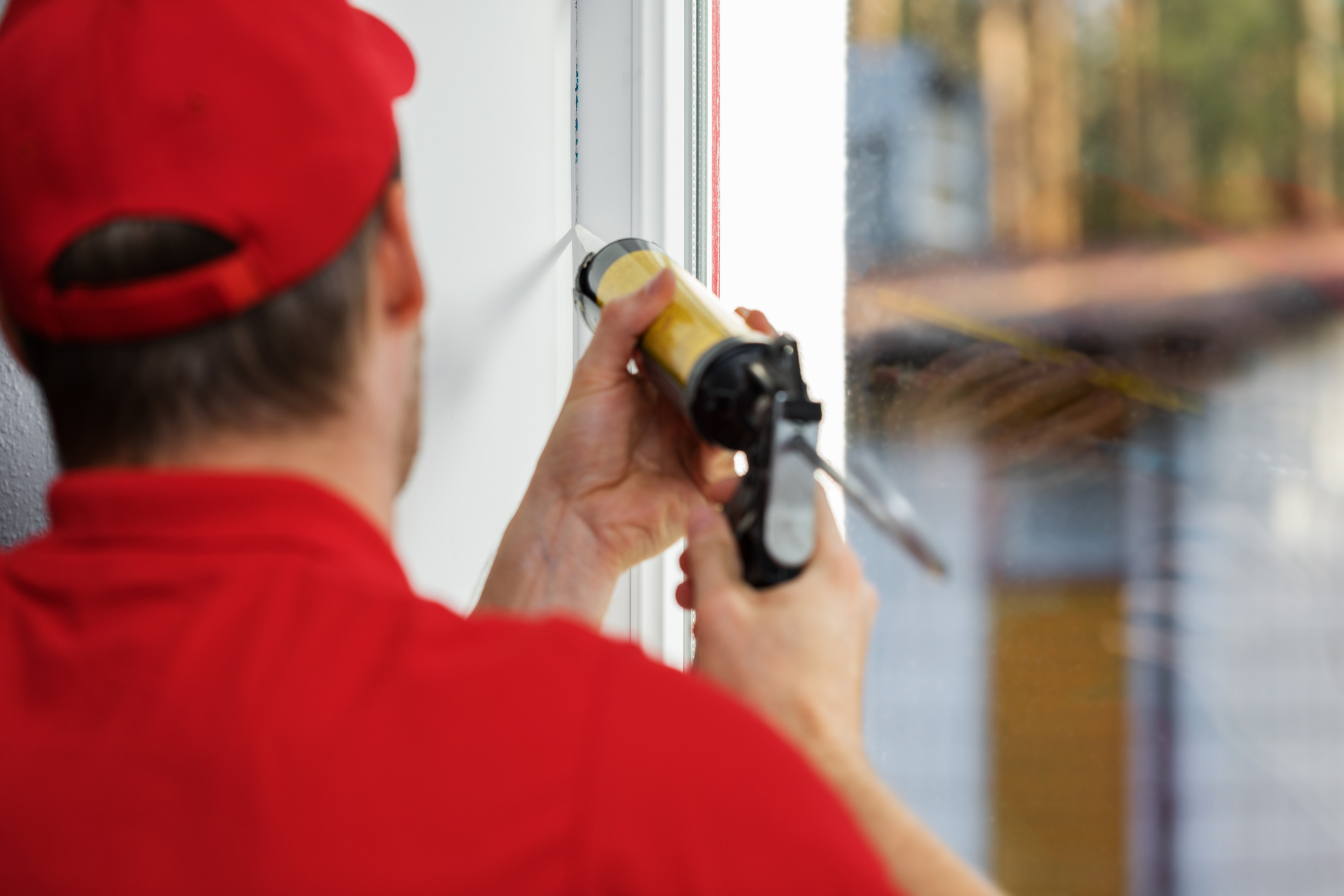 Window installer applying sealant around a replacement window during installation